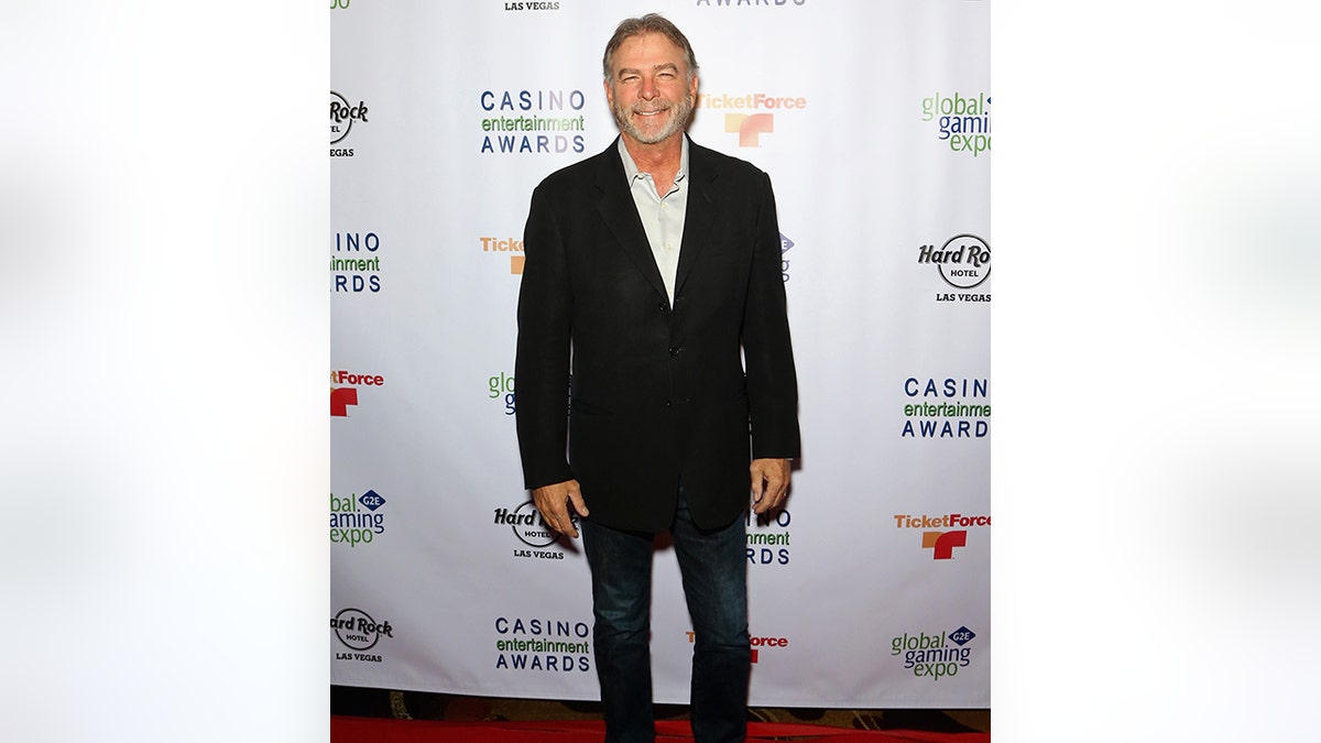 Bill Engvall in a black suit smiles on the carpet
