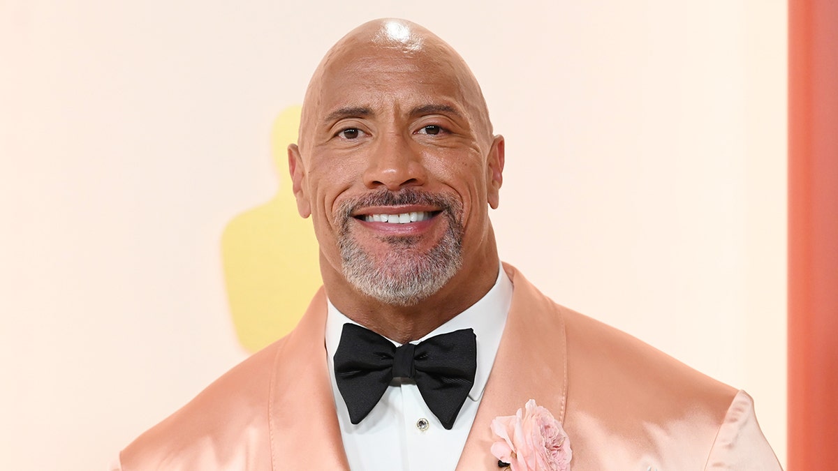 Dwayne Johnson in a light peach satin tuxedo with a black bow-tie on the Oscars carpet
