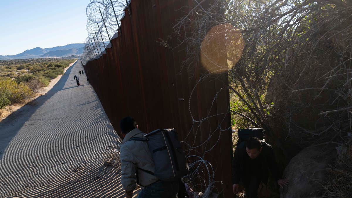 Migrants passs through the U.S.-Mexico border into California