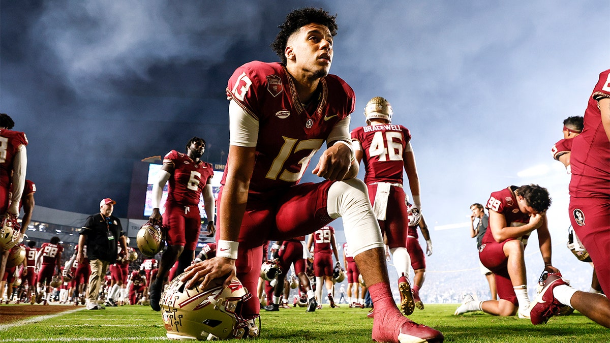 Jordan Travis kneels before a game