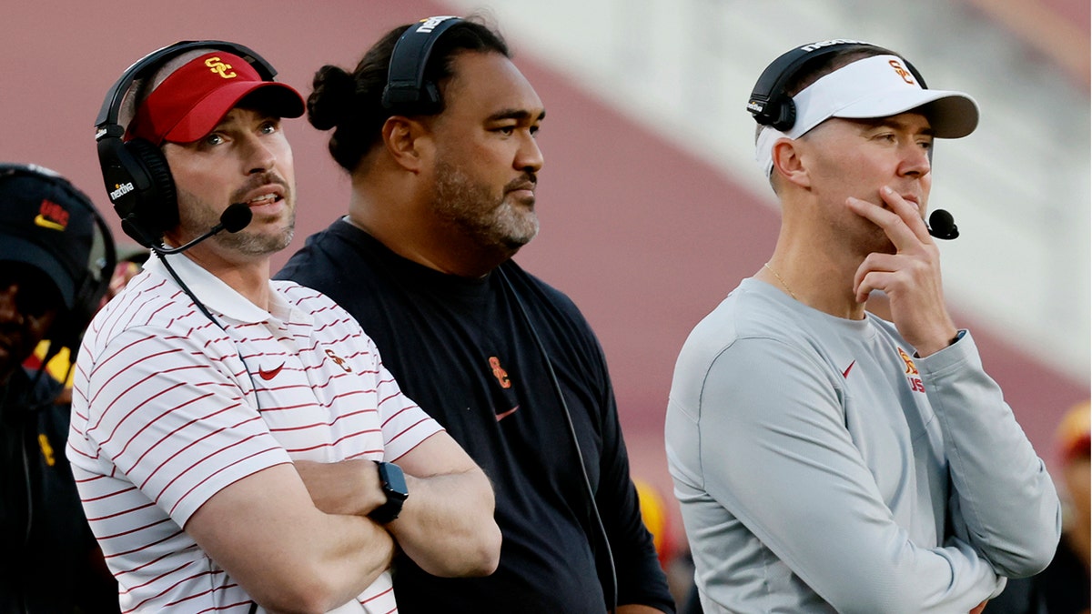 Alex Grinch and Lincoln Riley look on against Washington