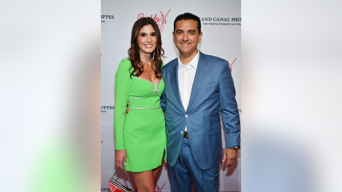 Buddy Valastro in a blue suit and white shirt next to his wife Lisa wearing a green dress