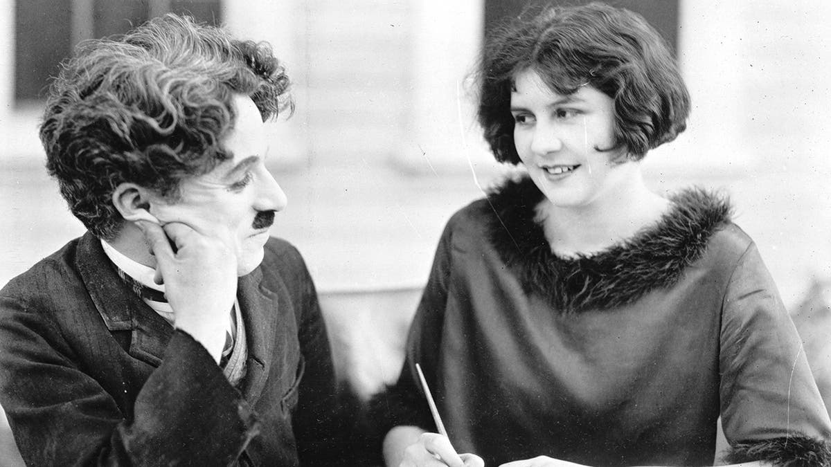 Charlie Chaplin dressed as the tramp looking adoringly at Lita Grey