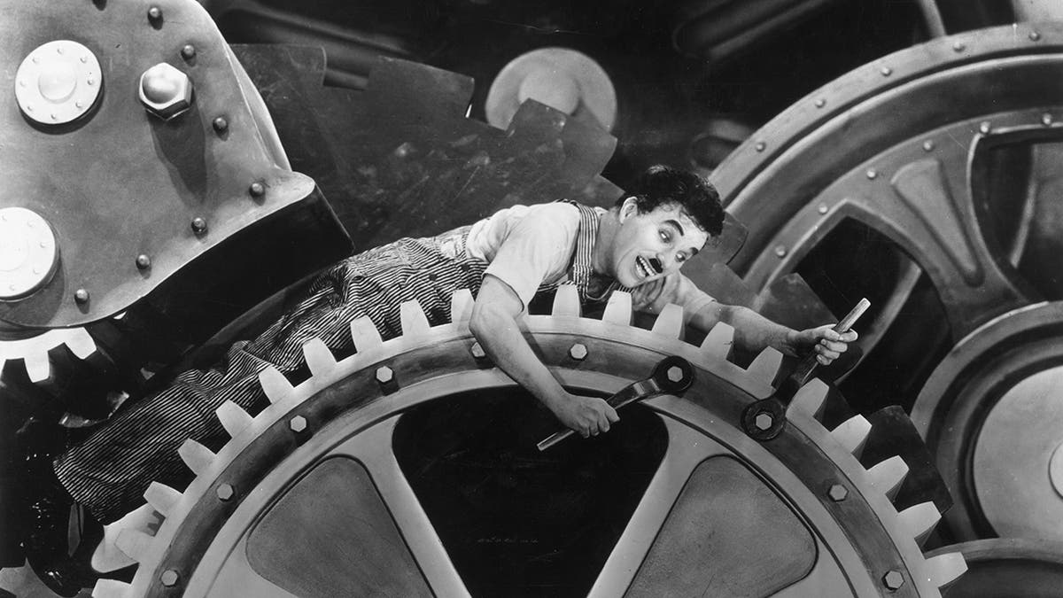 Charlie Chaplin wearing overalls on top of a giant wheel
