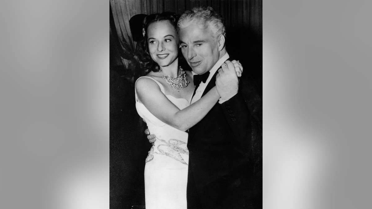 Charlie Chaplin dancing closely with a smiling Paulette Goddard in a white dress