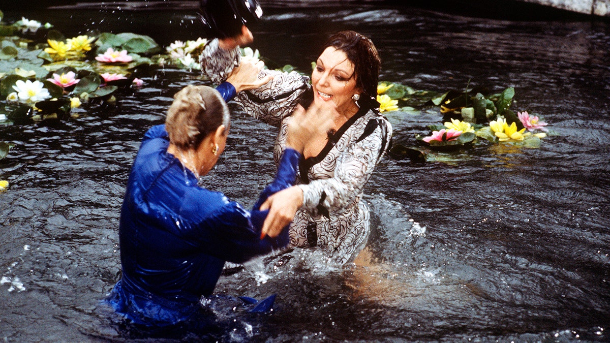 Joan Collins e Linda Evans brigando em um lago com lírios