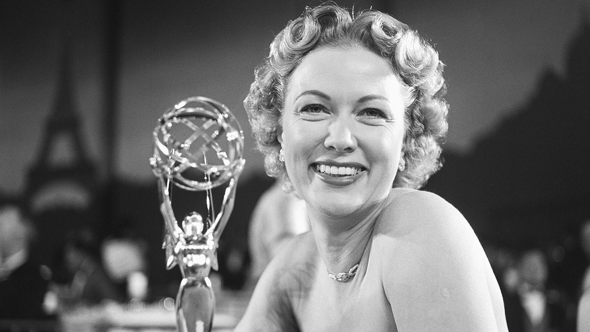Eleanor Powell sorrindo ao lado de seu prêmio Emmy