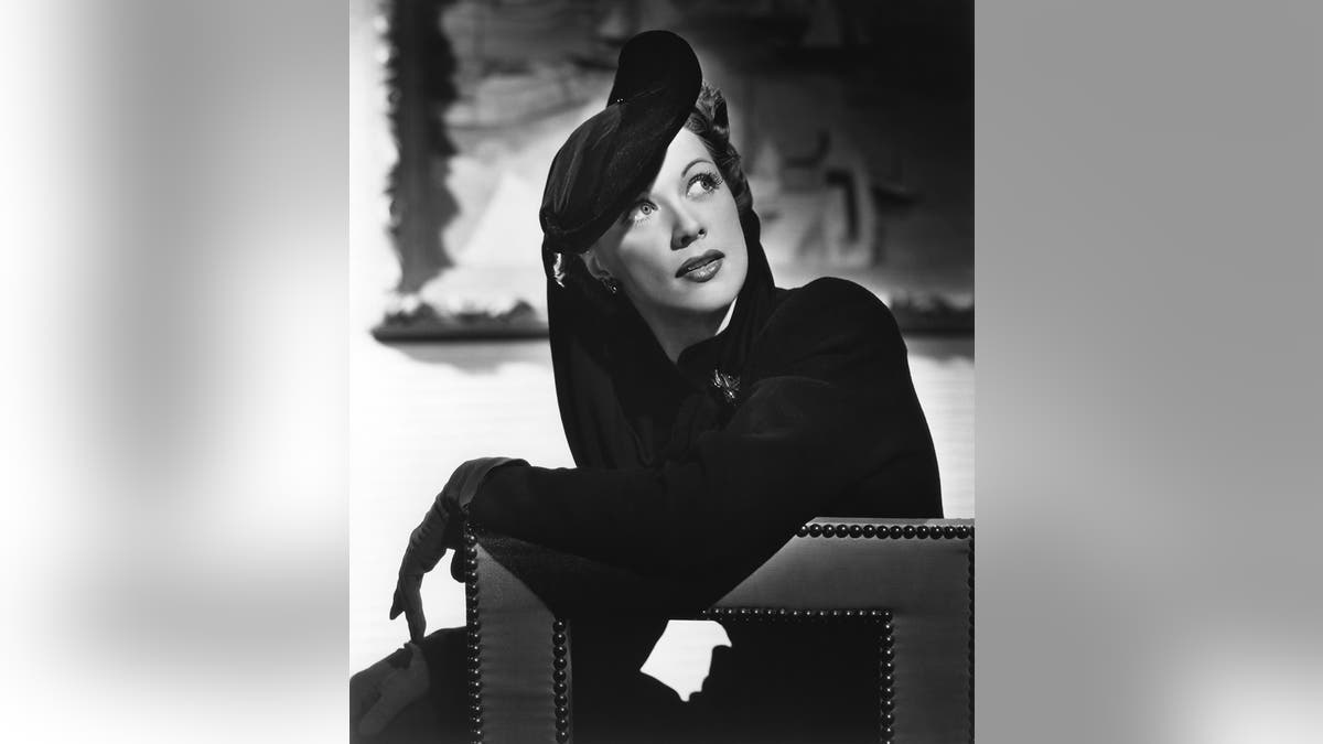 Eleanor Powell em um vestido preto glamoroso com chapéu combinando