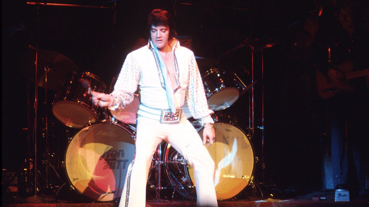 Elvis Presley se apresentando no palco vestindo um macacão