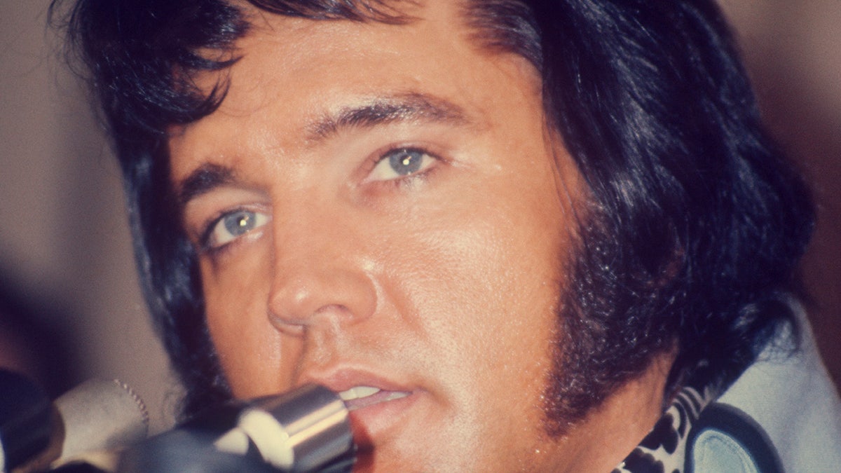 A close-up of Elvis Presley talking to a mic