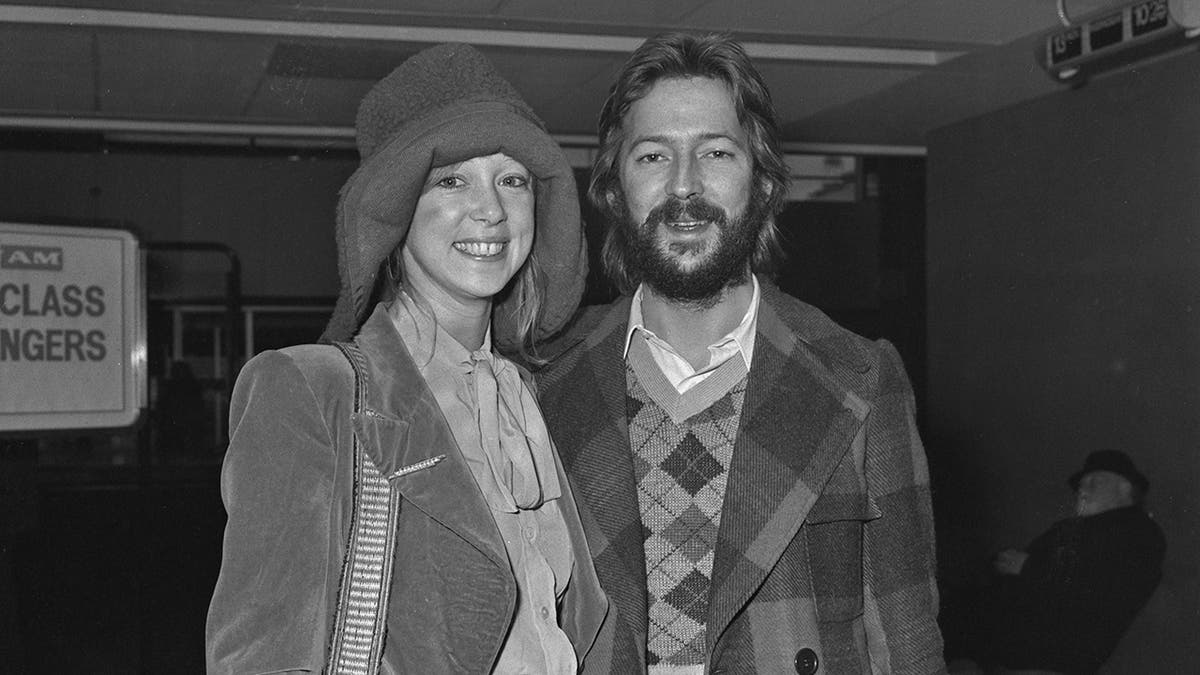 Eric Clapton and Pattie Boyd smiling next to each other wearing jackets