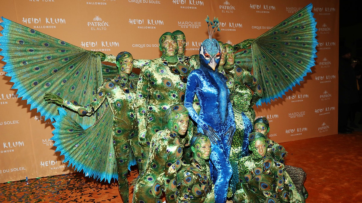 Heidi Klum e sua comitiva vestindo uma fantasia de pavão gigante