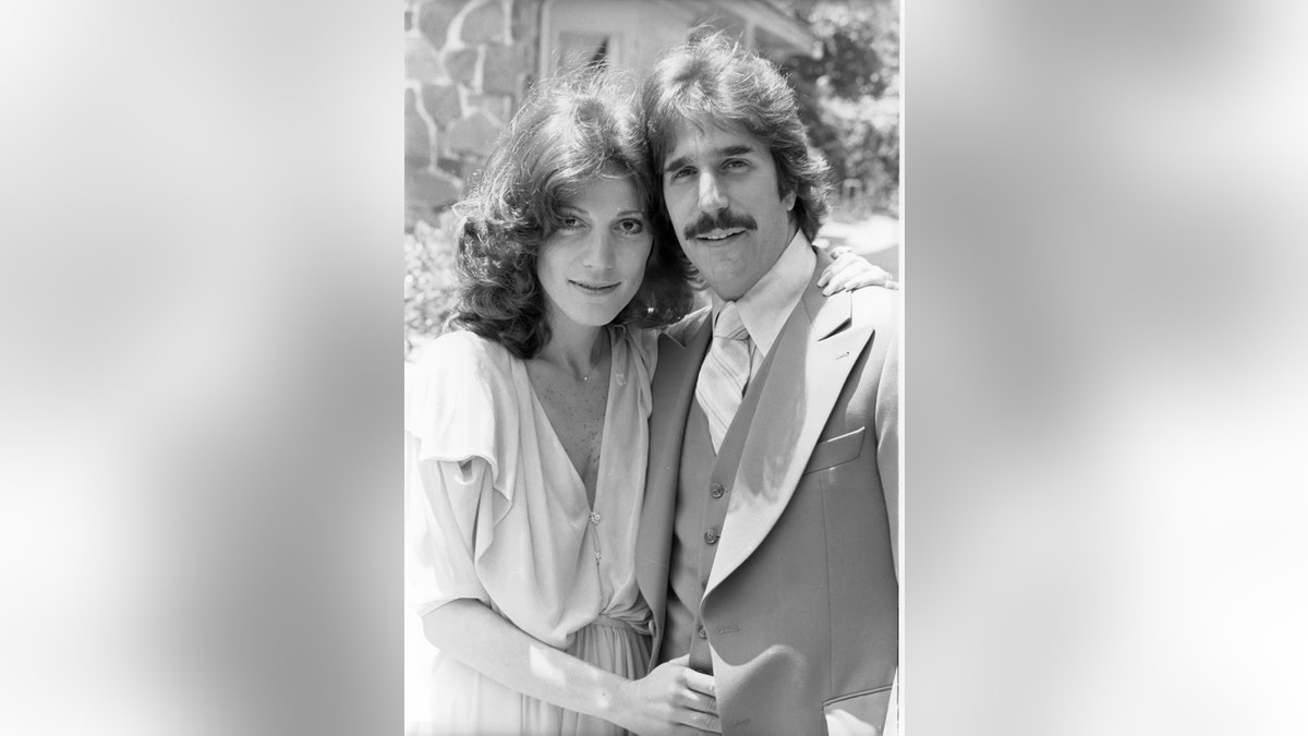 A black and white photo of Henry Winkler in a suit next to his wife Stacey in a white dress