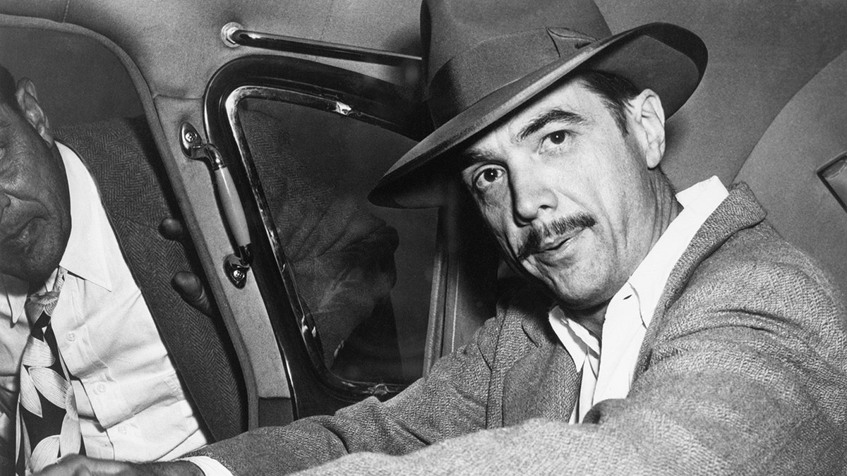 Howard Hughes seated in an automobile.