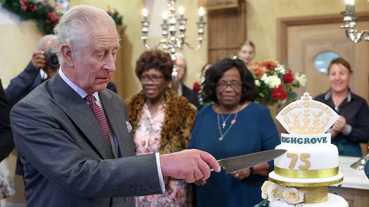 King Charles in a suit cutting his birthday cake
