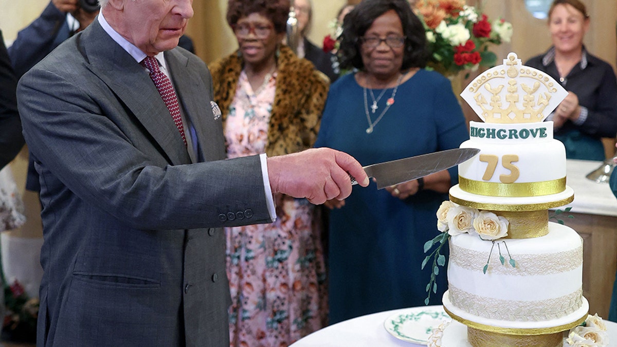 King Charles in a suit cutting his birthday cake