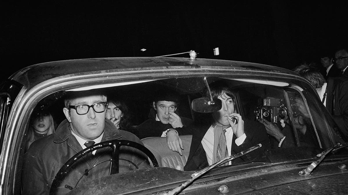 Mal Evans driving a car with the Beatles in the backseat