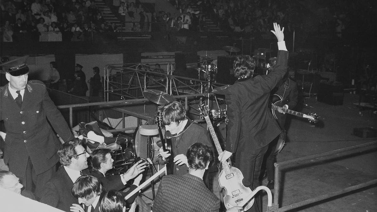 The Beatles stepping down off stage in the middle of a crowd