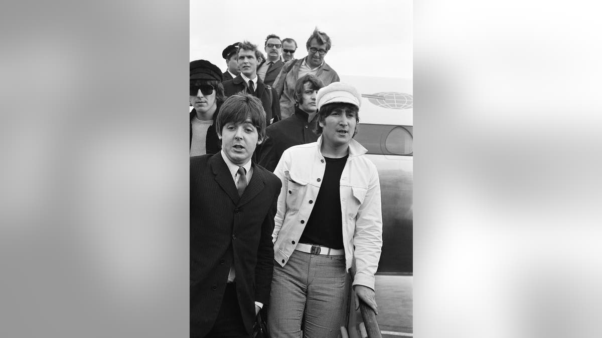 The Beatles walking outside of their plane in London