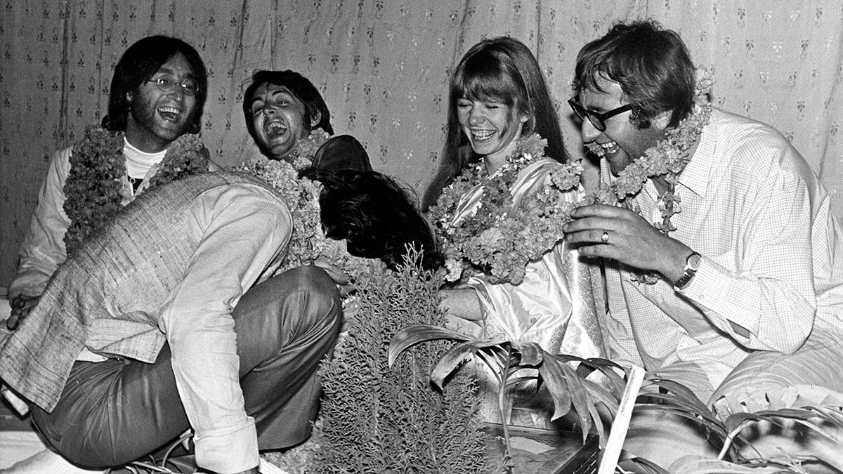 The Beatles all laughing and sitting down together in India