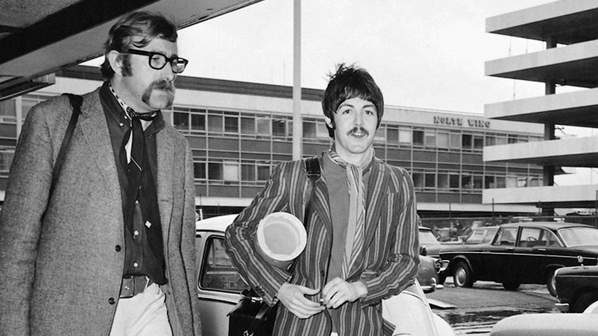 Mal Evans looking serious as he walks next to Paul mcCartney