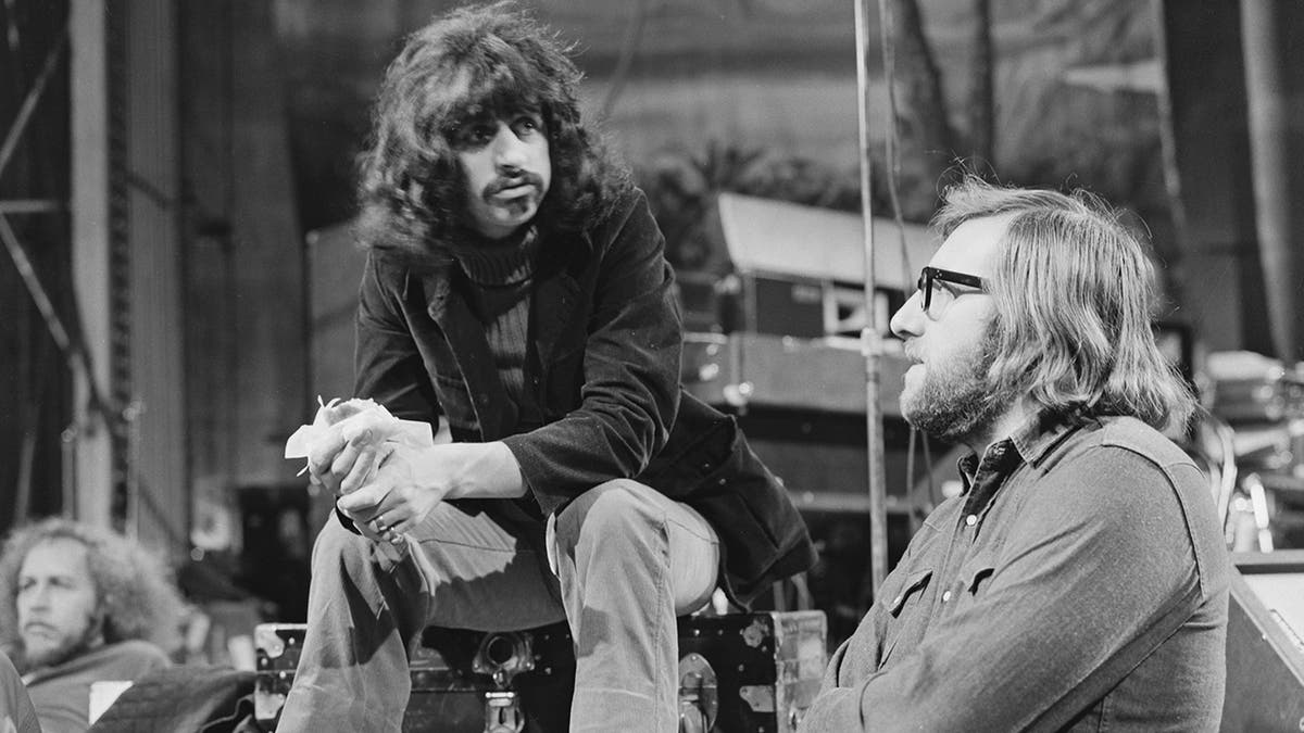 Mal Evans chatting with Ringo Starr as they both sit down