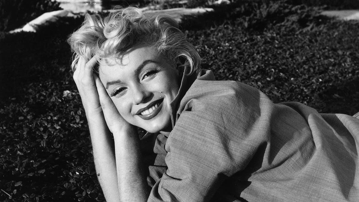 Marilyn Monroe leaning on her hands and smiling