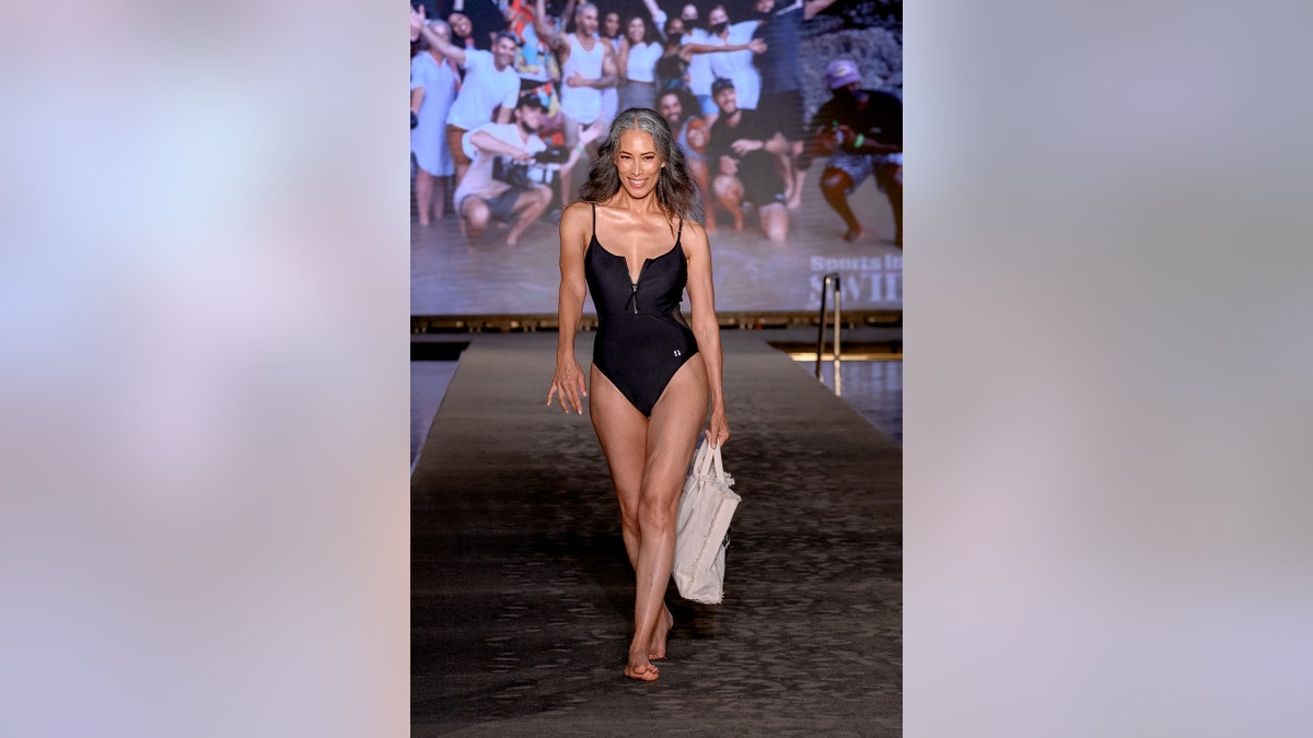 Nina Cash walking the runway in a black swimsuit