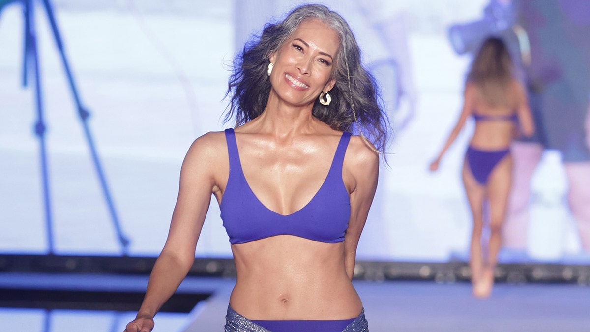 Close-up of Nina Cash walking the runway in a purple bikini