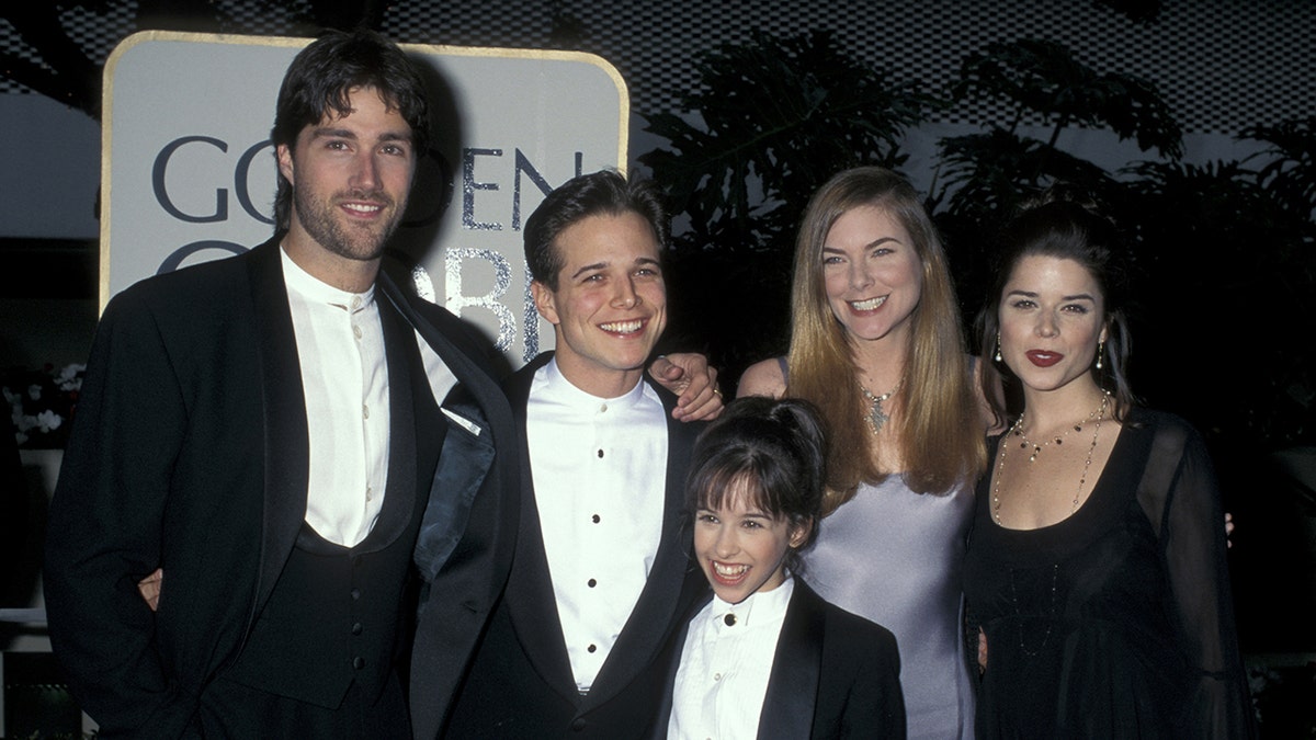 The cast of Party of Five smiling and wearing formal wear on the red carpet