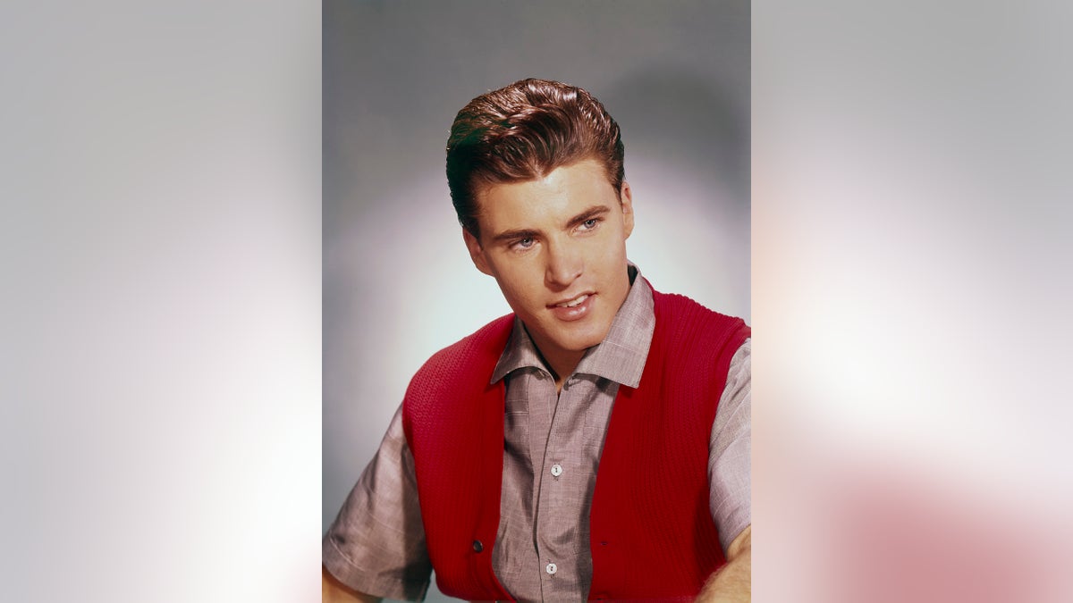 Ricky Nelson wearing a red shirt and a matching bright red vest