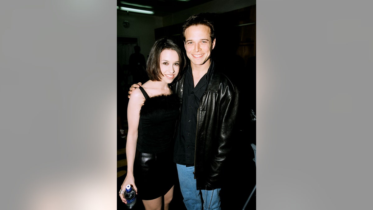 Lacey Chambert and Scott Wolf wearing matching black outfits