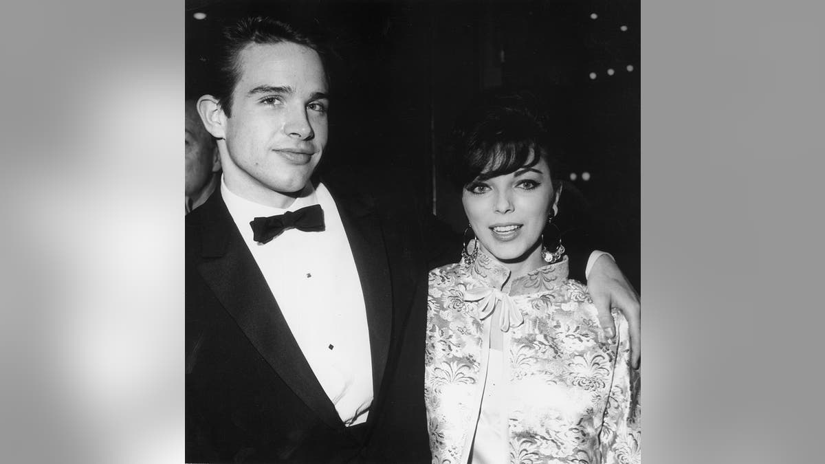 Warren Beatty in a tux embracing Joan Collins in a printed dress