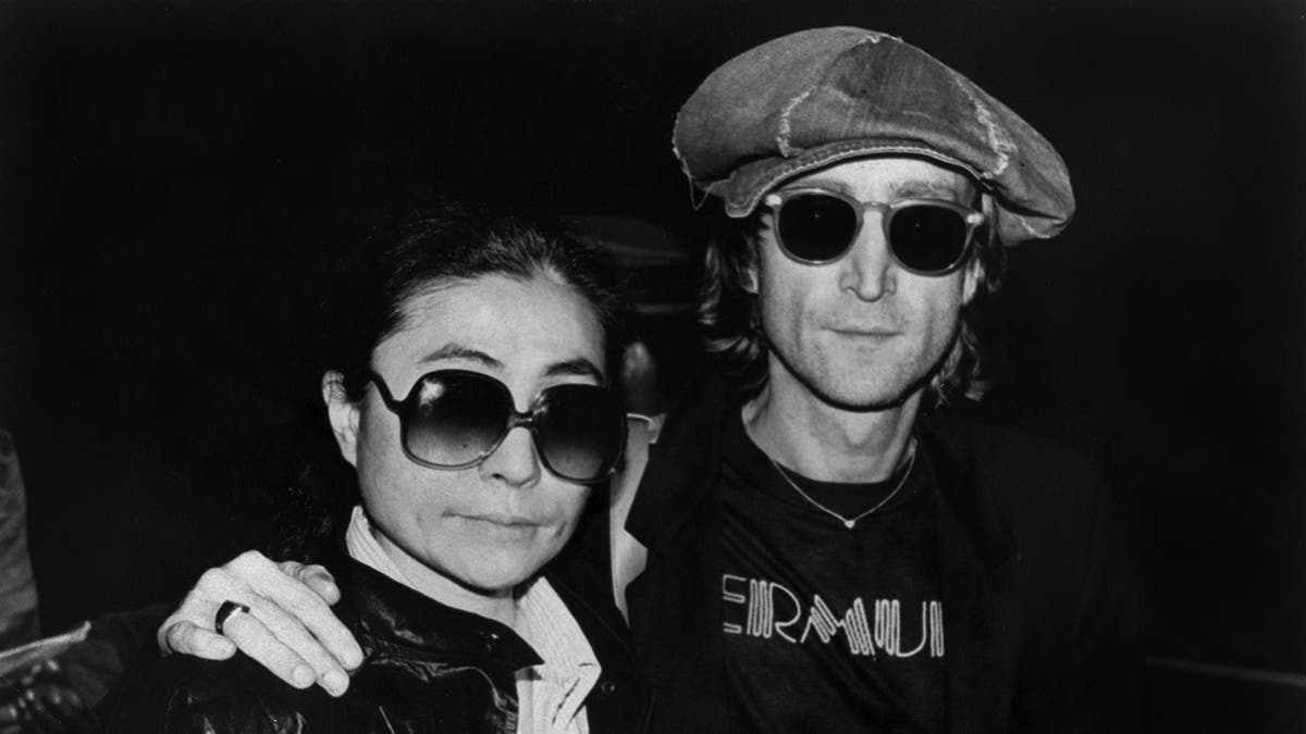 Yoko Ono being embraced by John Lenoon as they wear matching sunglasses