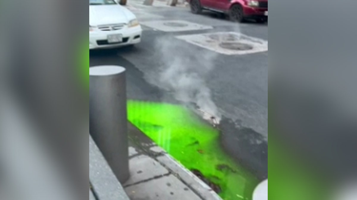 Bright green water leaking out of New York City sewers onto street by cars