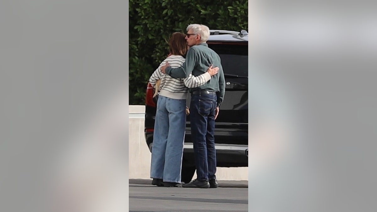 Harrison Ford and Calista Flockhart with their arms around each other at the airport