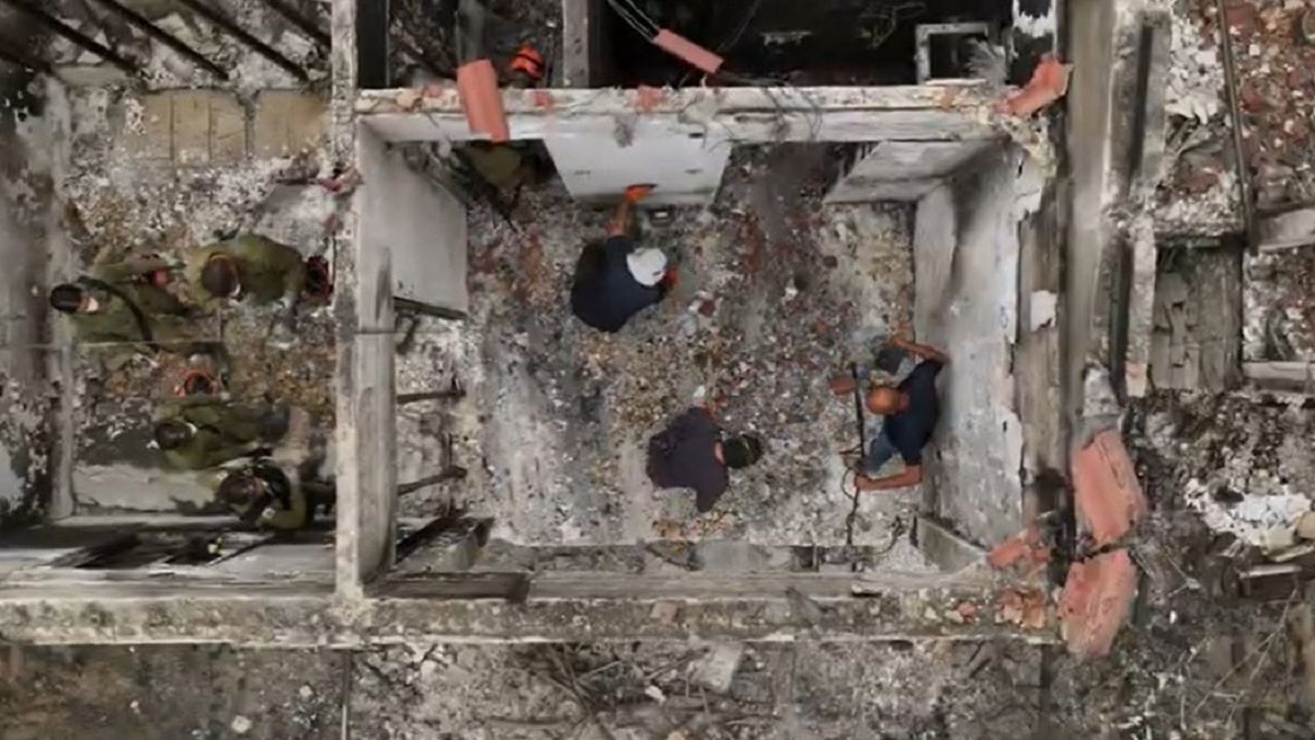 Aerial view of archaeologists sifting through debris in a burnt home in Israel.