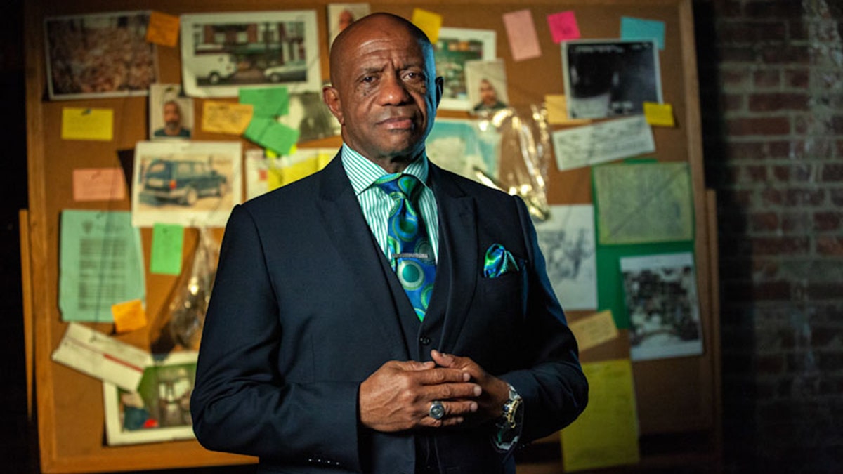 Garry McFadden in front of a bulletin wearing a suit