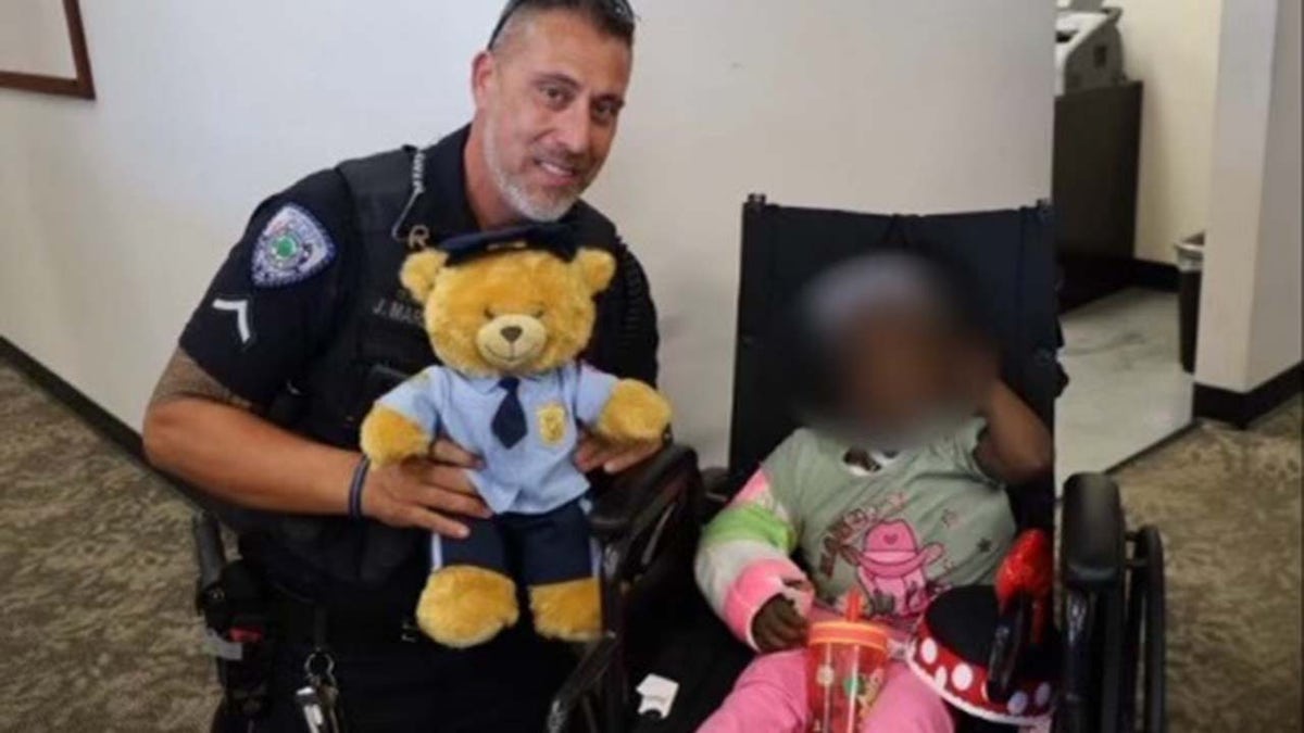 The police officer who saved a toddler who fell from a moving car poses with the teddy bear presented to her.