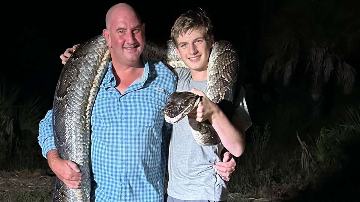 MICHAEL AND COLE ELFENBEIN pose with captured python