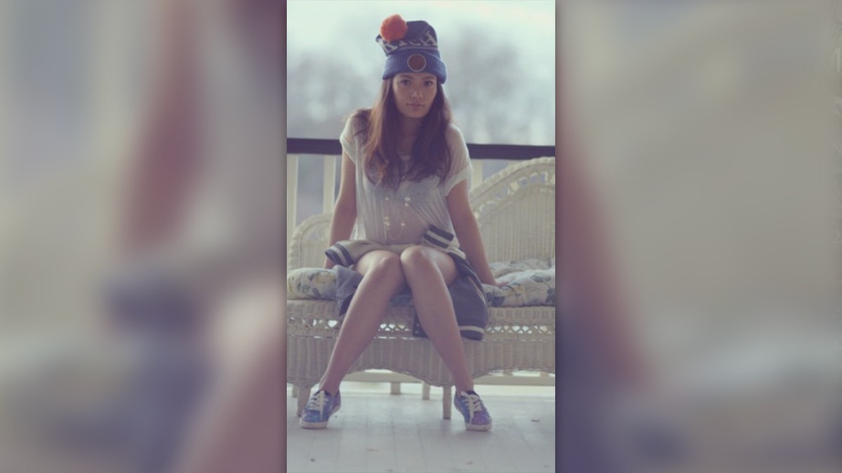 Mei Haskell poses on a wicker bench