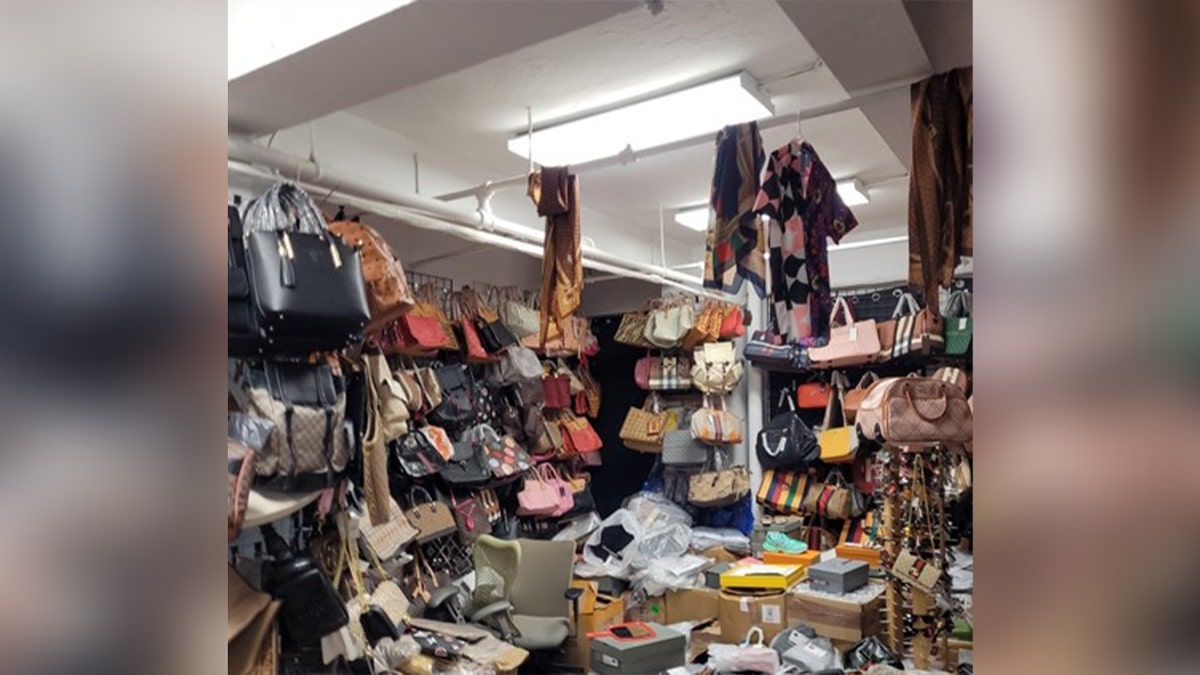 fake designer bags filled in a room and clothes hang from a pipe