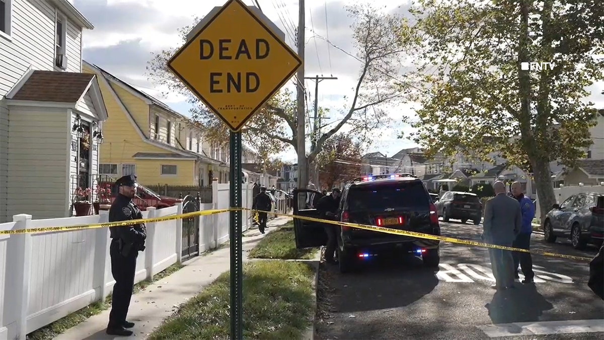 A dead end sign and police tape and a police van outside a house in New York City where three people were fatally stabbed