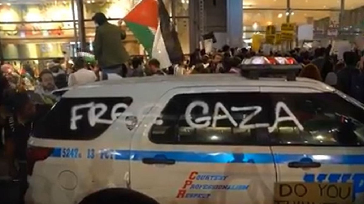 NYPD vehicle surround by pro-Palestinian rioters in New York.