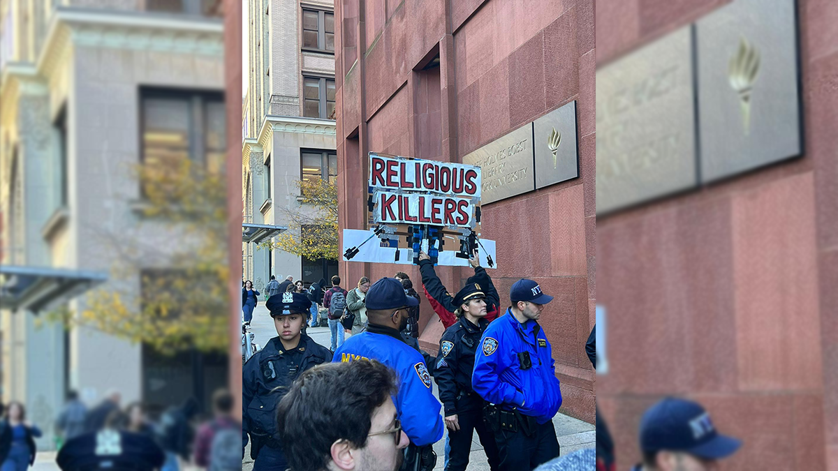 Manifestante en la Universidad de Nueva York con un cartel que dice 'Asesinos religiosos'