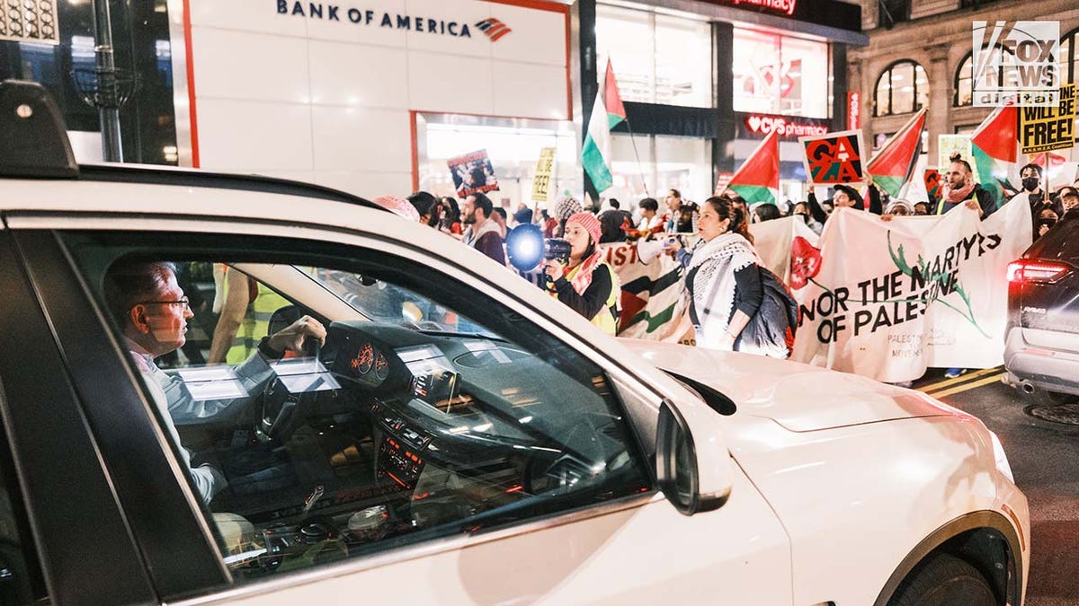 A driver attempts to navigate through streets filled with pro-Palestine protestors