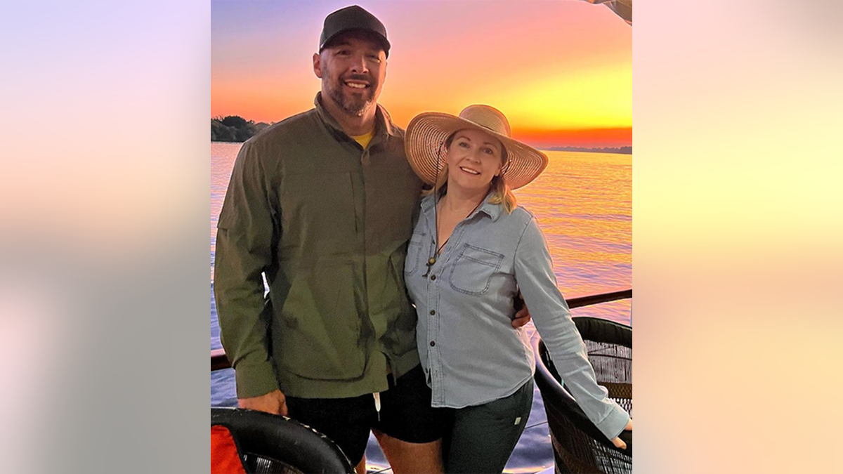 Melissa Joan Hart con un grande cappello da sole posa accanto al marito Mark Wilkerson su una barca in Zambia con un tramonto sullo sfondo
