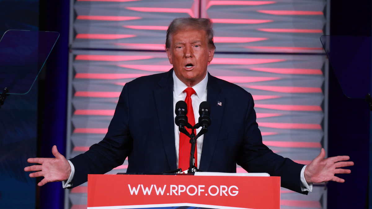 Donald Trump speaks in Florida behind a podium in a navy suit