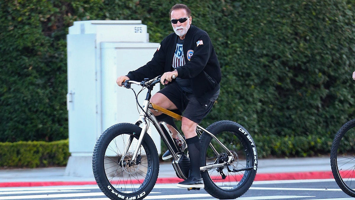 Arnold Schwarzenegger rides his bicycle on city streets in Santa Monica