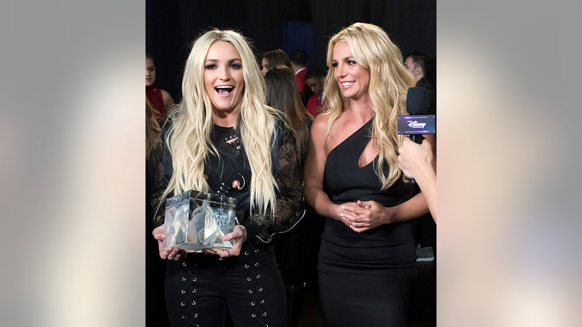 Jamie Lynn Spears laughs as she stands next to sister Britney, both wearing black